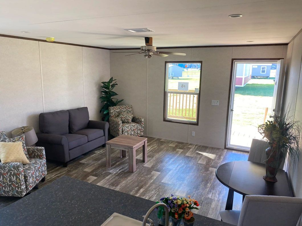 A living room with a couch , chairs , table and a ceiling fan.