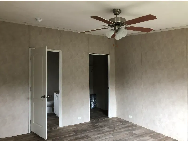 An empty room with a ceiling fan hanging from the ceiling