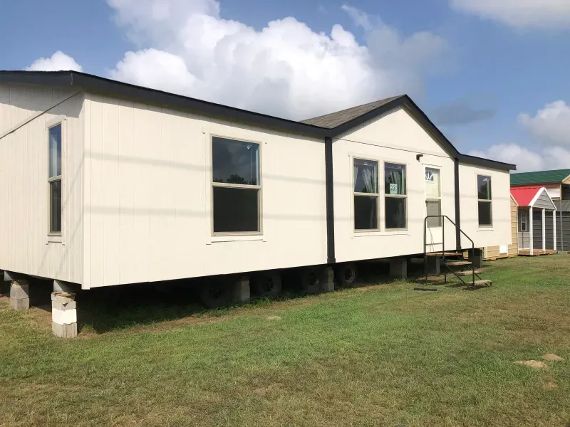 A mobile home is parked in a grassy field.