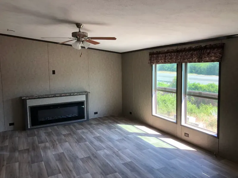 An empty living room with a fireplace and a ceiling fan.
