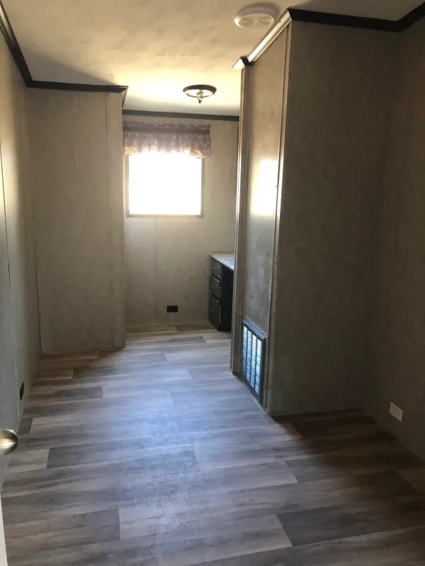 An empty room with a wooden floor and a window.