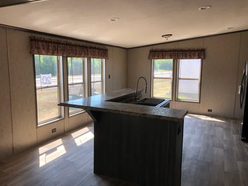 A kitchen in a mobile home with a large island and a sink.