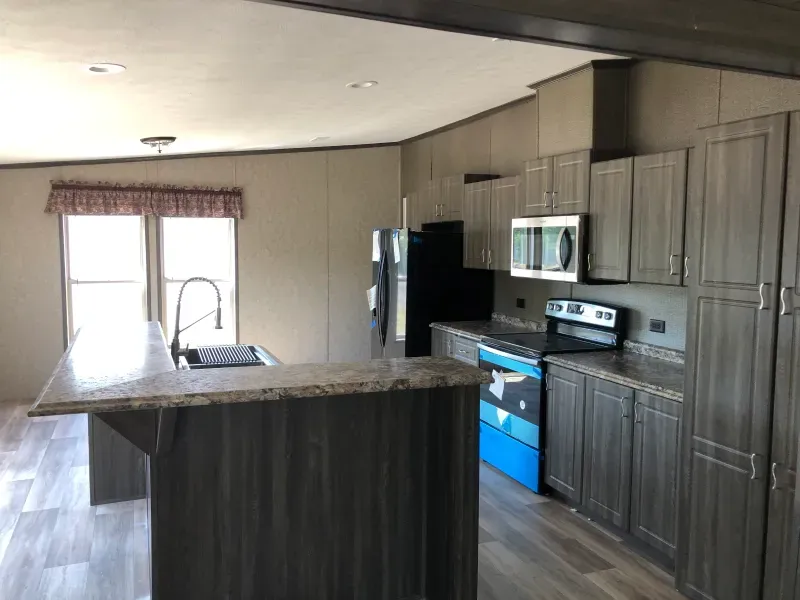 A kitchen with a stove , refrigerator , microwave and sink.