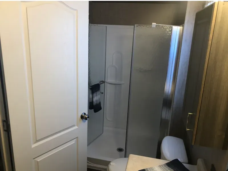 A bathroom with a toilet , shower and mirror.