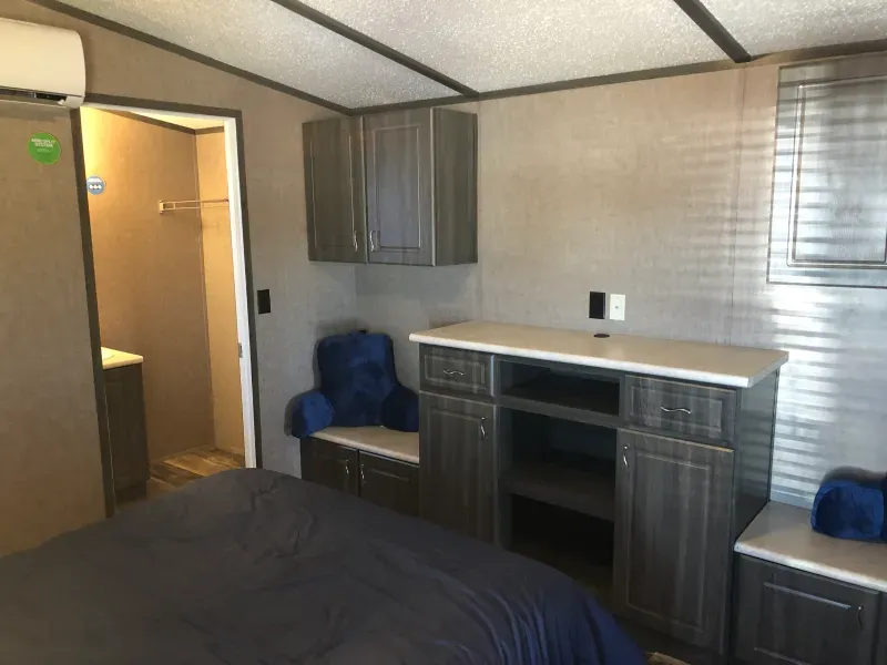 A bedroom with a bed , cabinets and a chair