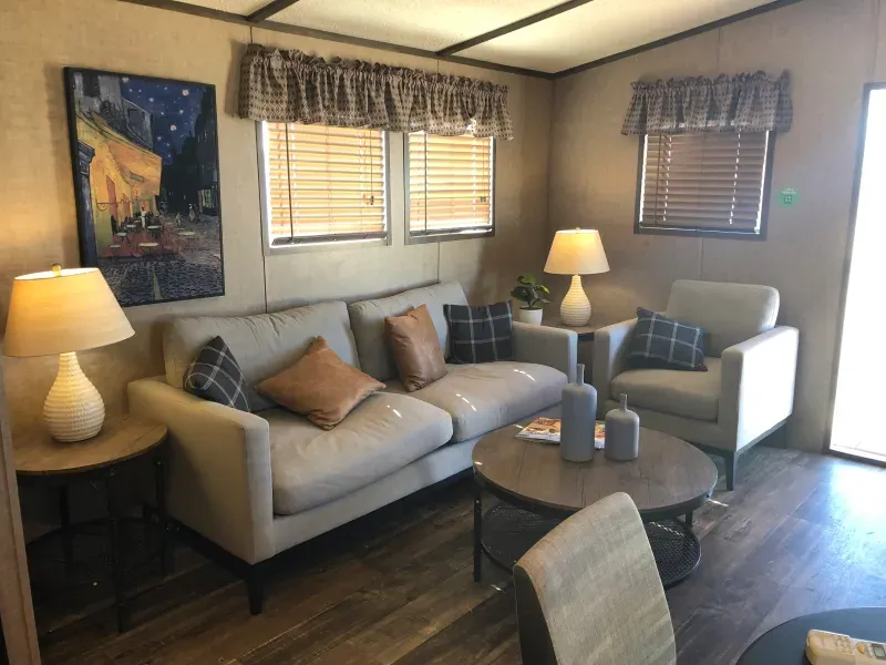 A living room with a couch , chairs , lamps and a table.