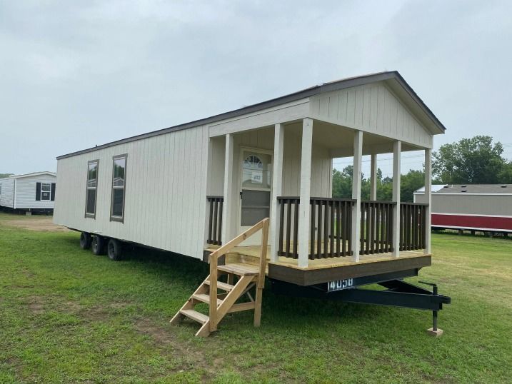 A mobile home with a porch and stairs on a trailer.