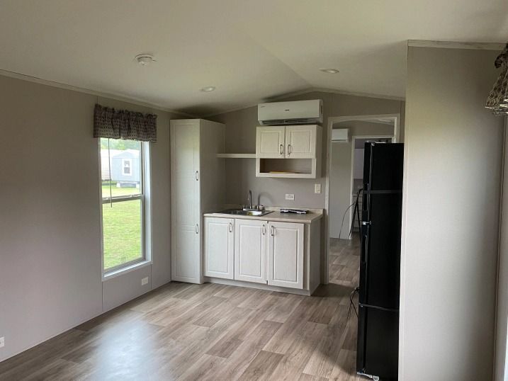 A living room with a kitchen and a refrigerator in a mobile home.