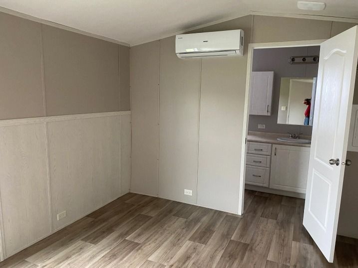 An empty room with hardwood floors and a bathroom in the background.