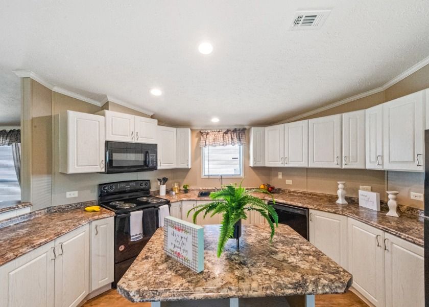 A kitchen in a mobile home with granite counter tops and white cabinets.