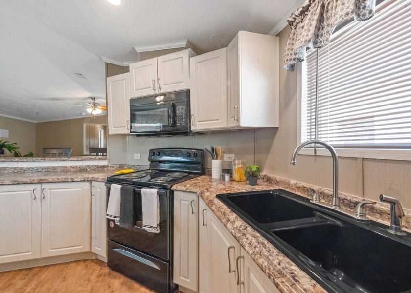 A kitchen with a sink , stove , microwave and window.