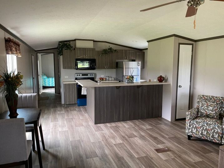 A living room filled with furniture and a kitchen in a mobile home.