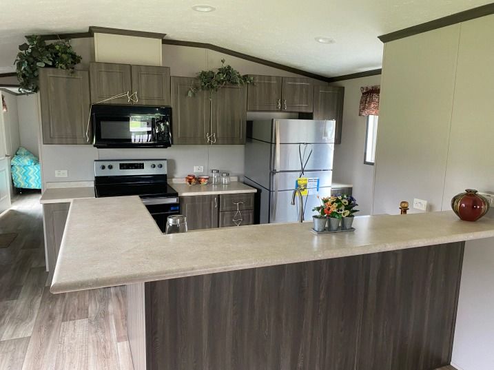 A kitchen with a stove , refrigerator , microwave and counter top.