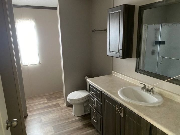 A bathroom with a toilet , sink and mirror.
