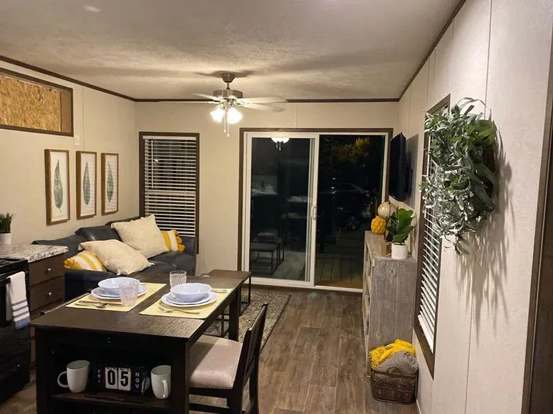 A living room with a couch , table , chairs and a sliding glass door.