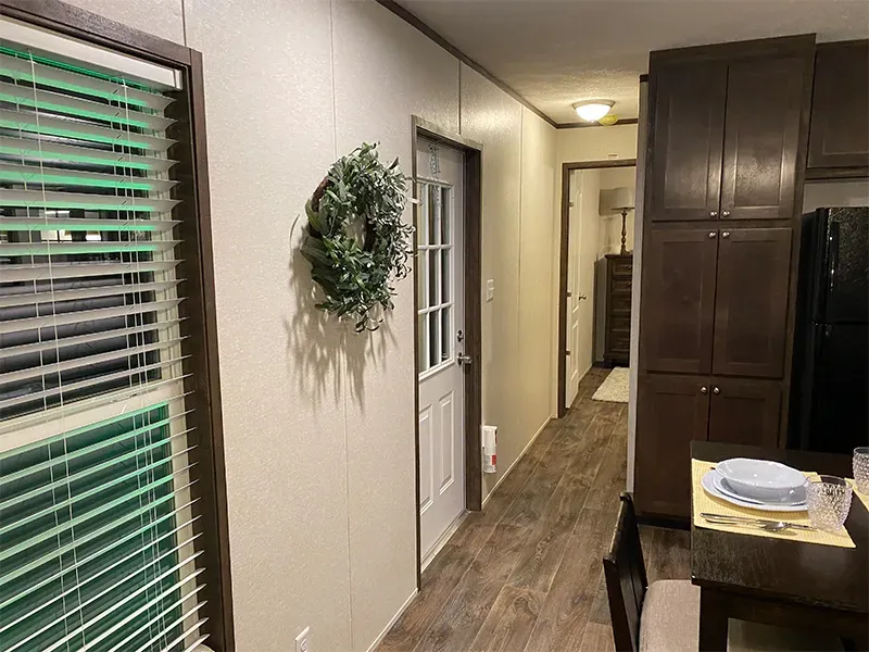 A hallway in a mobile home with a table and chairs.