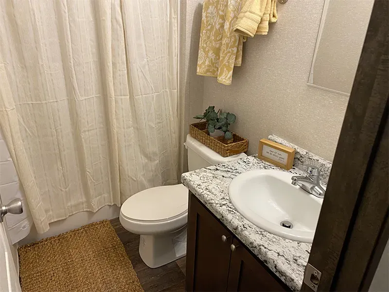 A bathroom with a toilet , sink , and shower curtain.