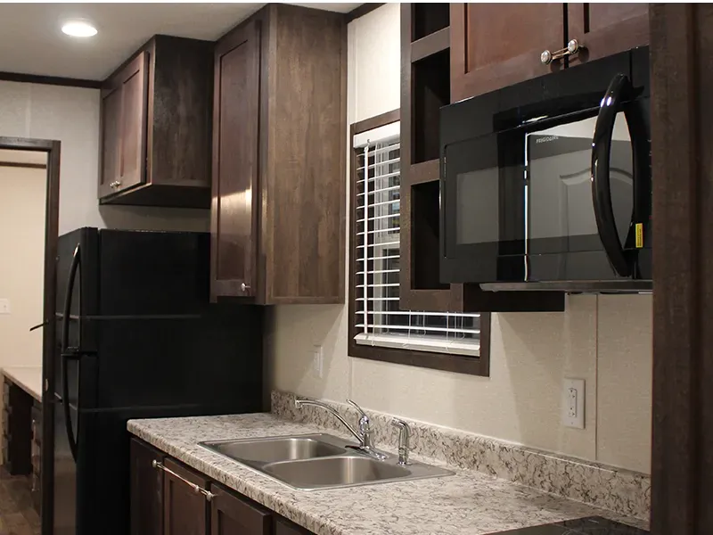 A kitchen with a sink , microwave , refrigerator and window.