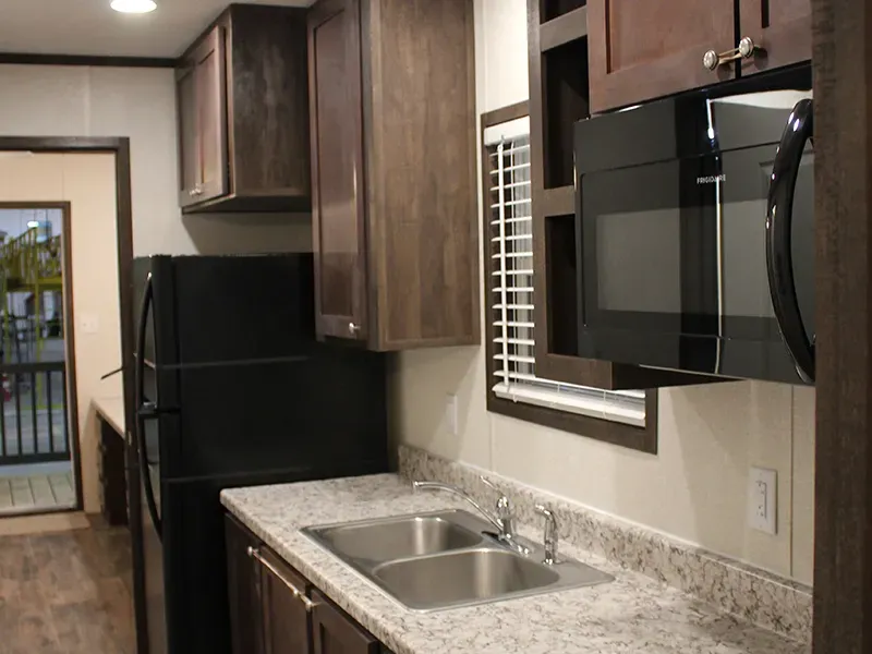 A kitchen with a sink , refrigerator and microwave.