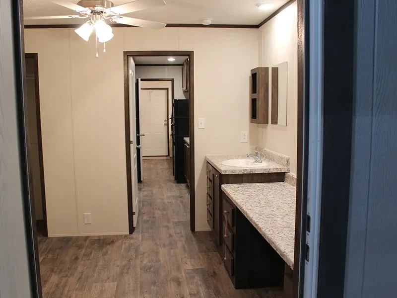 A hallway in a house with a sink and a ceiling fan.