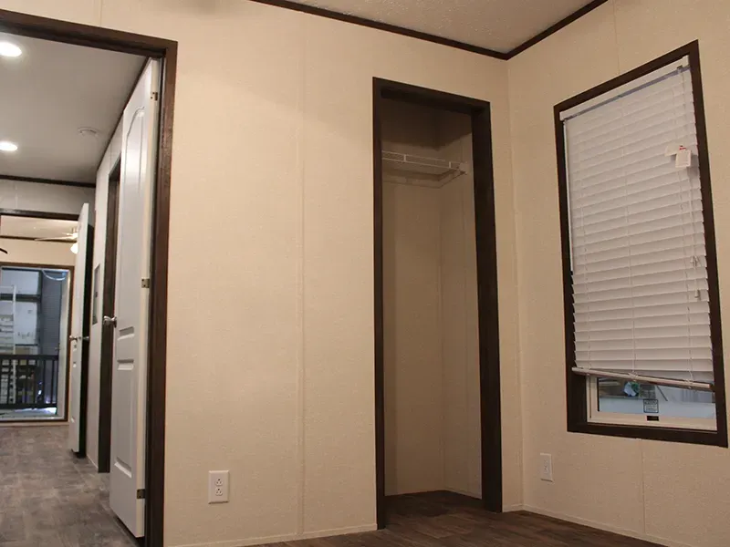 An empty room with a closet and two windows
