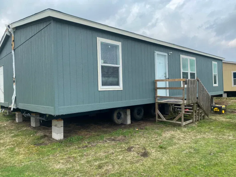 A mobile home is sitting in the middle of a grassy field.