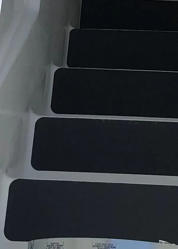 A close up of a set of black stair pads on a set of white stairs.