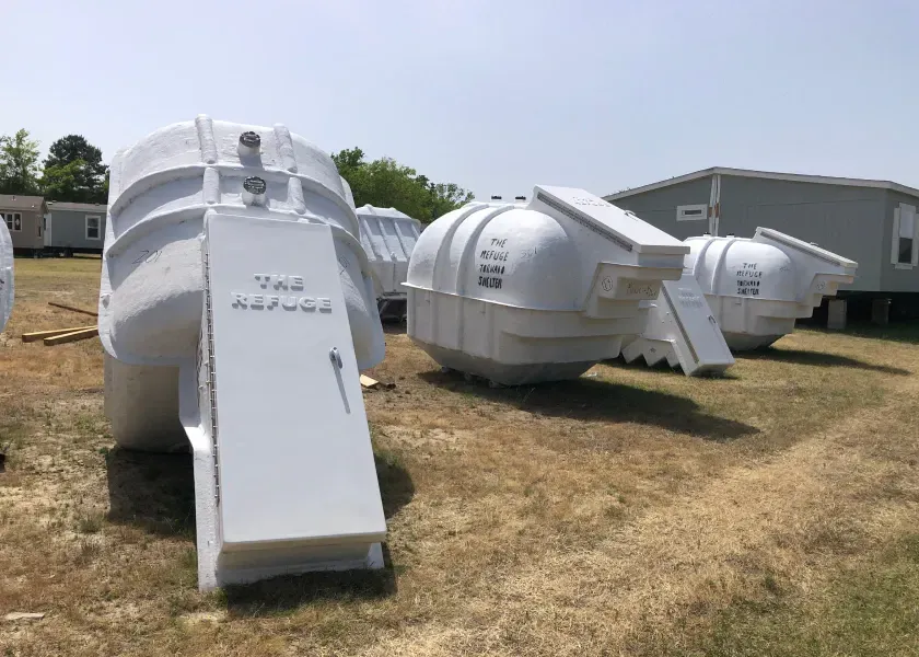 A row of white containers are sitting in a field.