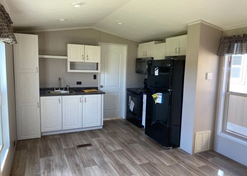 A kitchen in a mobile home with a refrigerator , stove , sink and microwave.