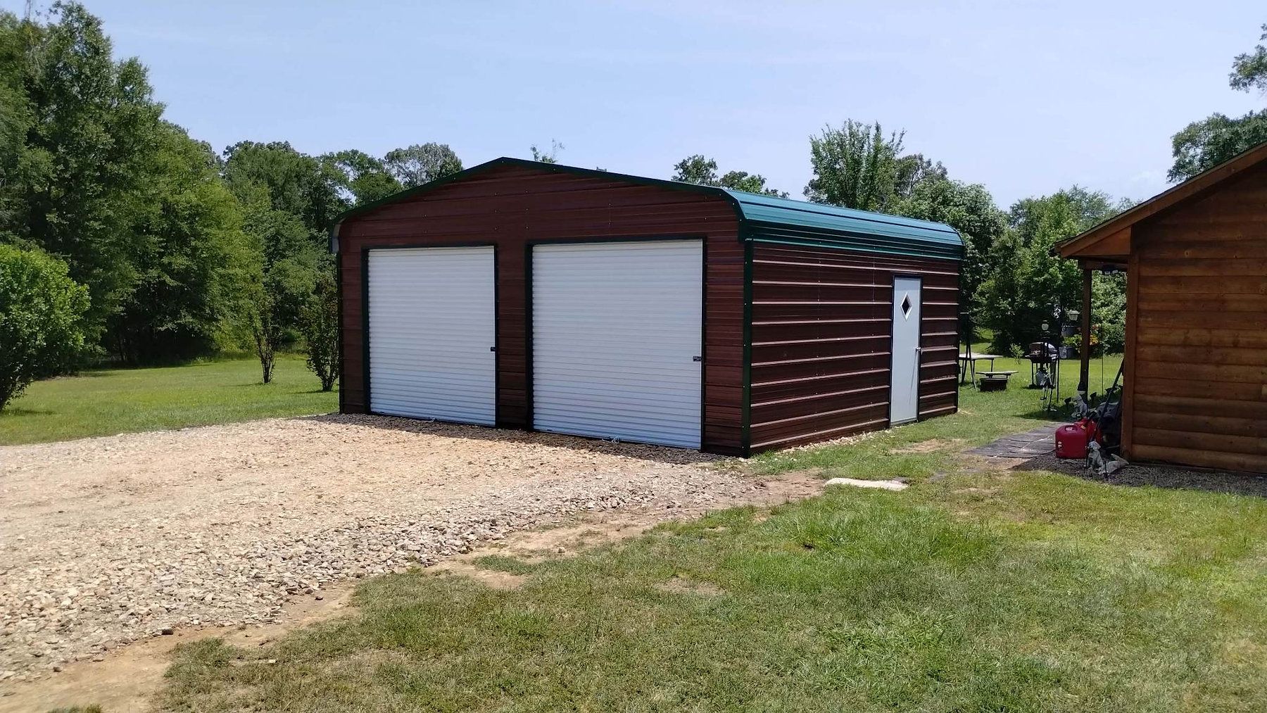 A garage with two doors is sitting in the middle of a grassy field.