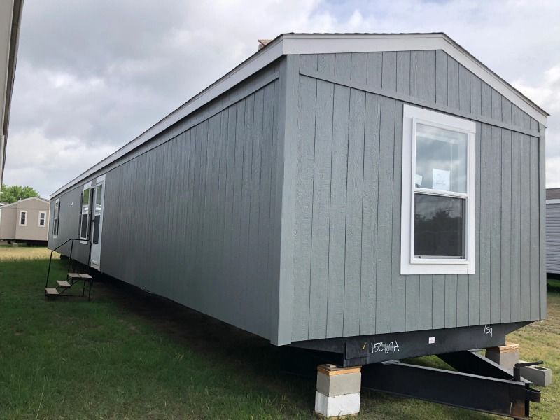 A mobile home is sitting on top of a trailer in a grassy field.