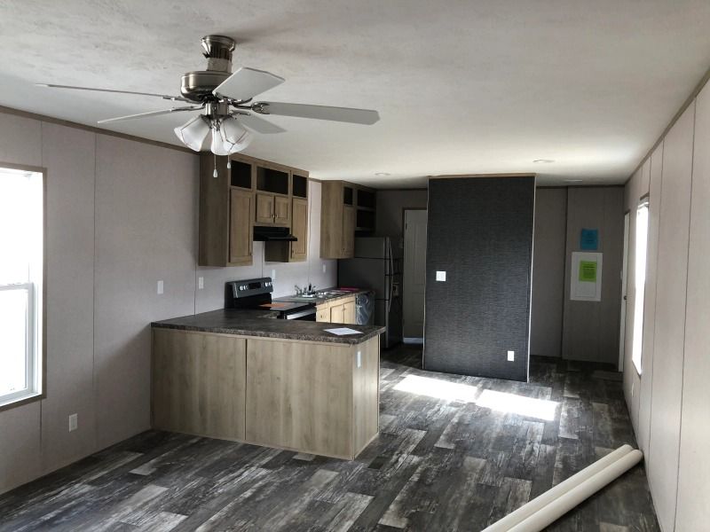 An empty room with a kitchen and a ceiling fan