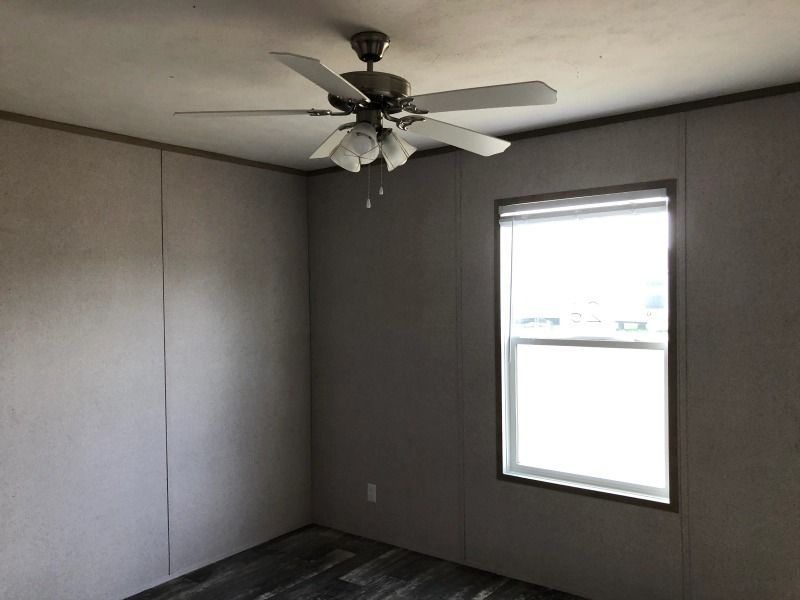 An empty room with a ceiling fan and a window