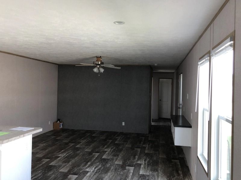 A living room with a ceiling fan and two windows