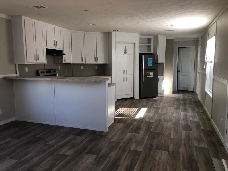 A kitchen with white cabinets and a black refrigerator