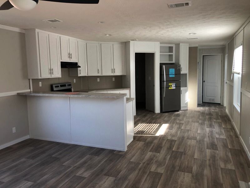 A kitchen with white cabinets , a refrigerator , and a ceiling fan.