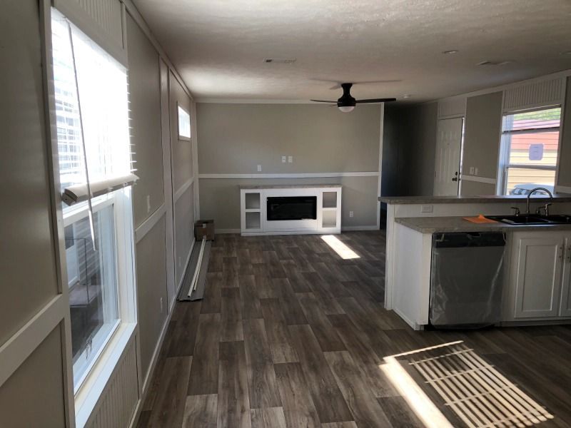 A living room with a fireplace and a ceiling fan in a mobile home.