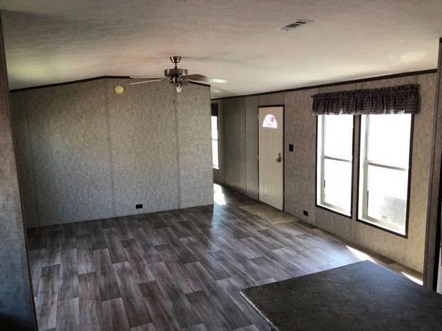 A living room in a mobile home with wooden floors and a ceiling fan.