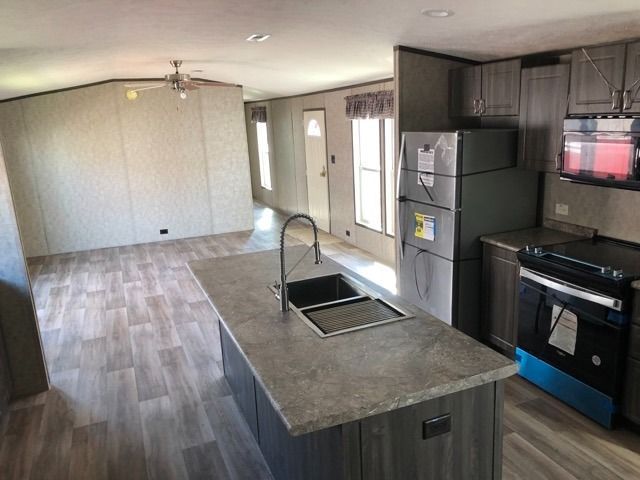 A kitchen with a sink , refrigerator , stove and microwave.