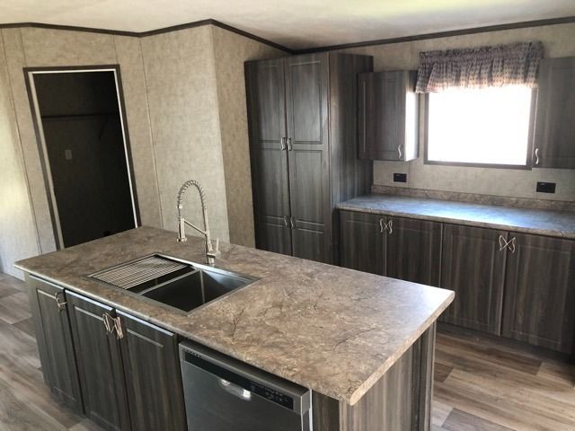 A kitchen with a sink , dishwasher , and cabinets.