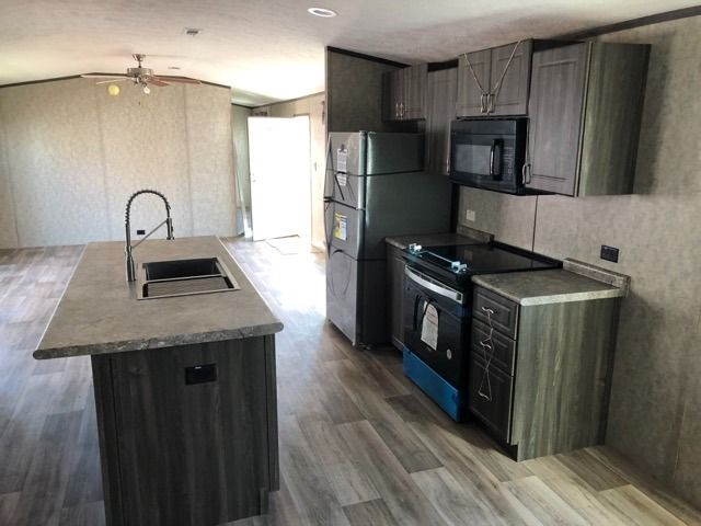 A kitchen with a refrigerator , stove , microwave and sink.
