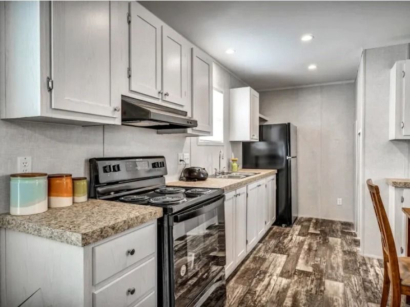 A kitchen with white cabinets , a stove , a refrigerator , and a sink.