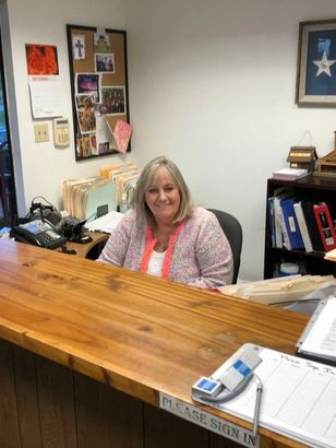 A woman sitting at a desk with a sign that says please sign in