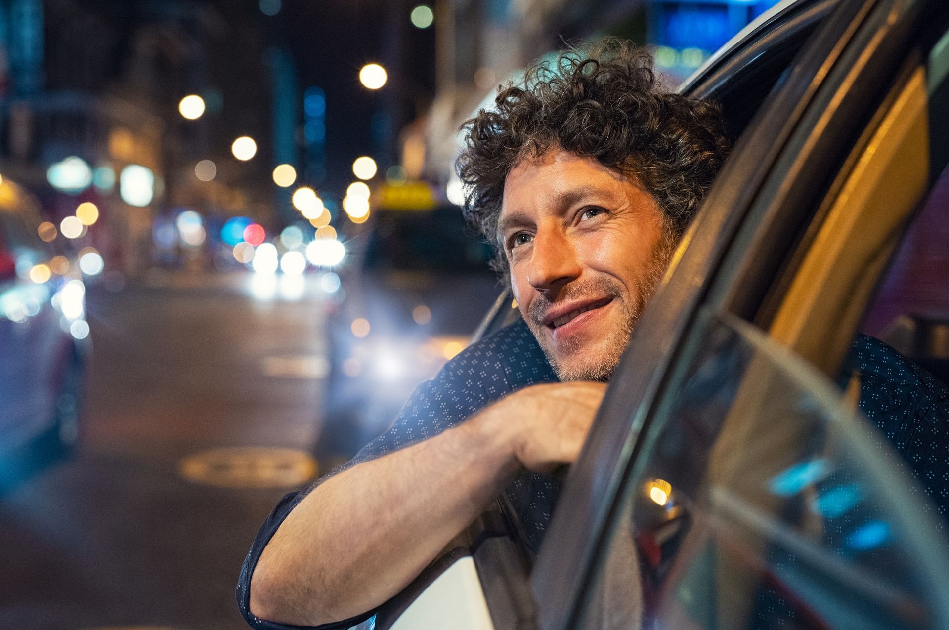 A man is looking out of the window of a car at night.
