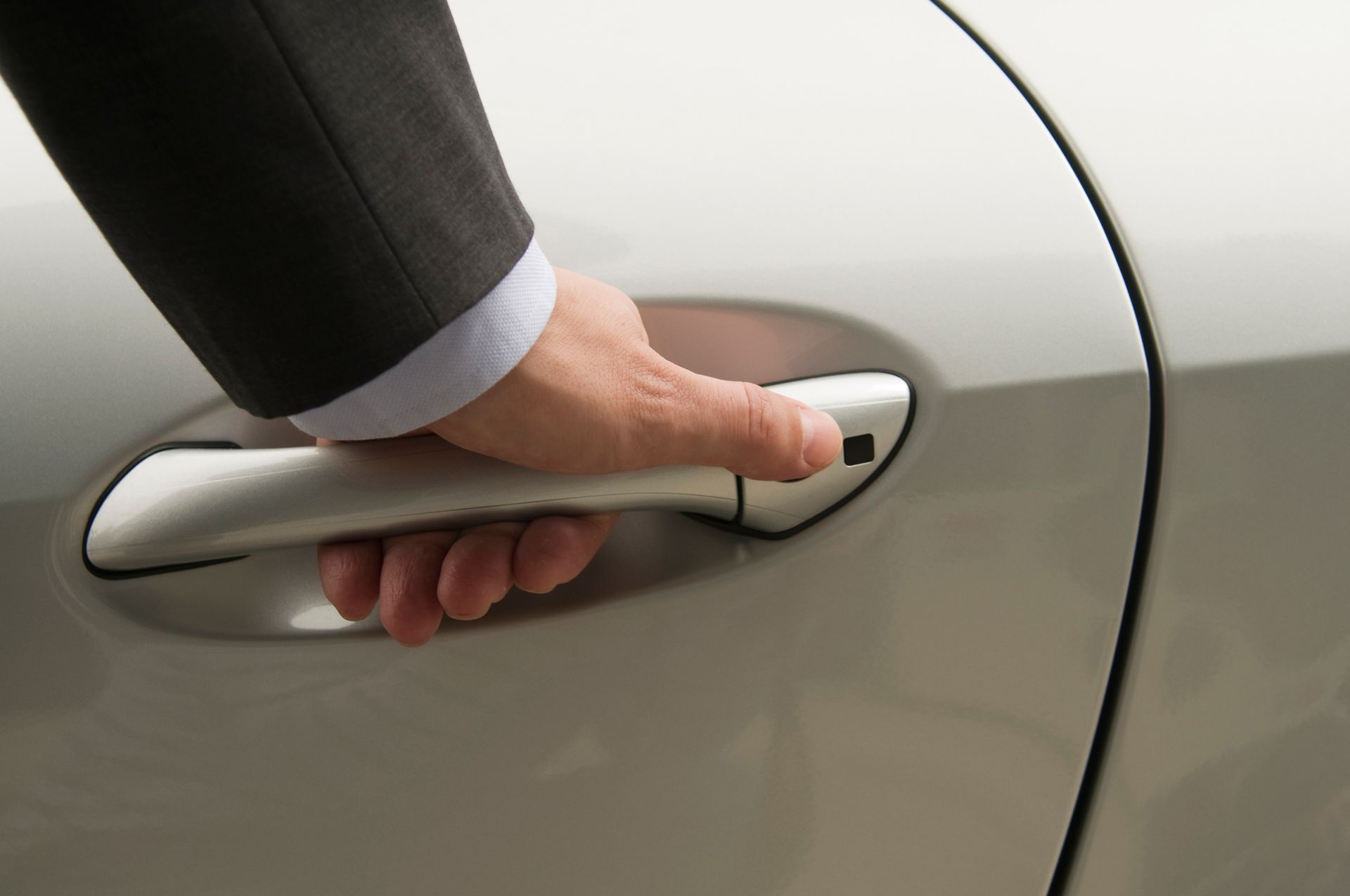 A man in a suit is opening the door of a car.