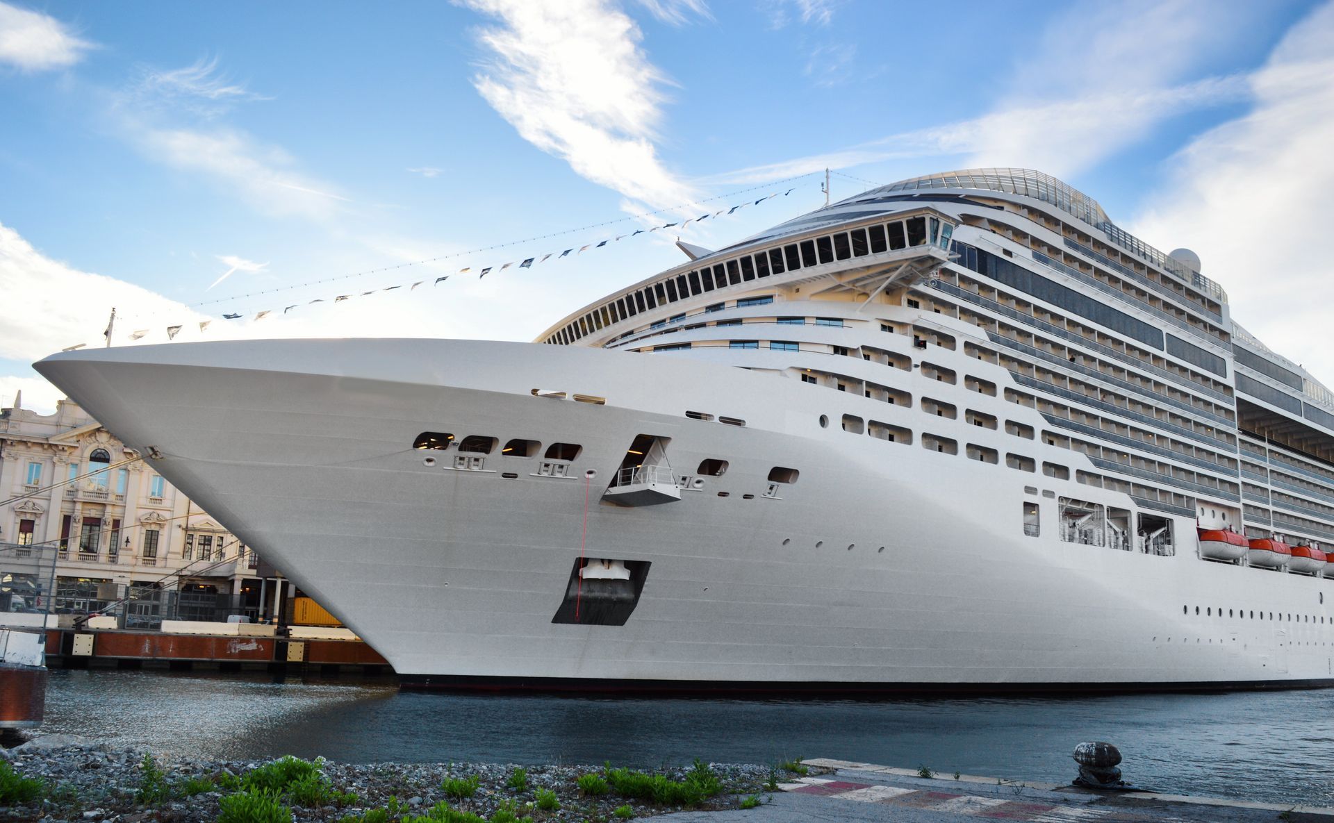 A large white cruise ship is docked in a harbor