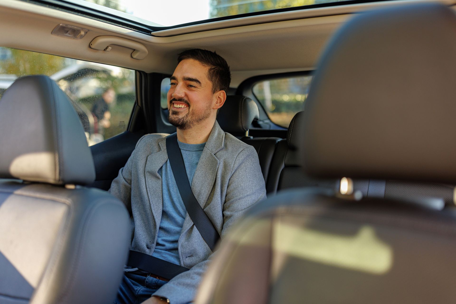 A man is sitting in the back seat of a car.
