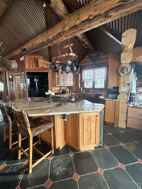 Rustic kitchen with a large island, wooden cabinets, and a pot rack.