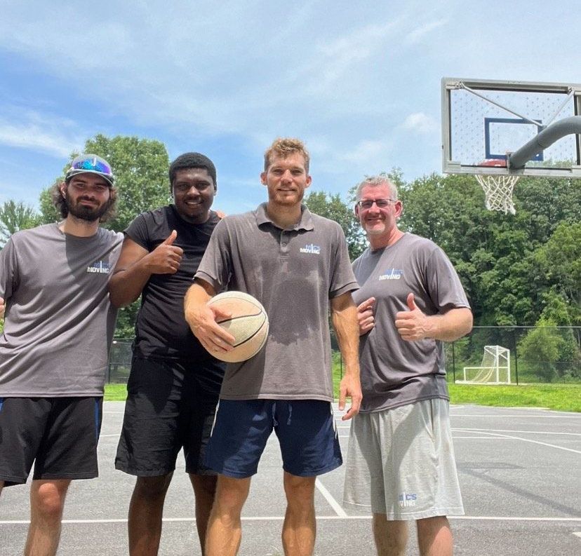 A group of men are standing in front of a moving truck.