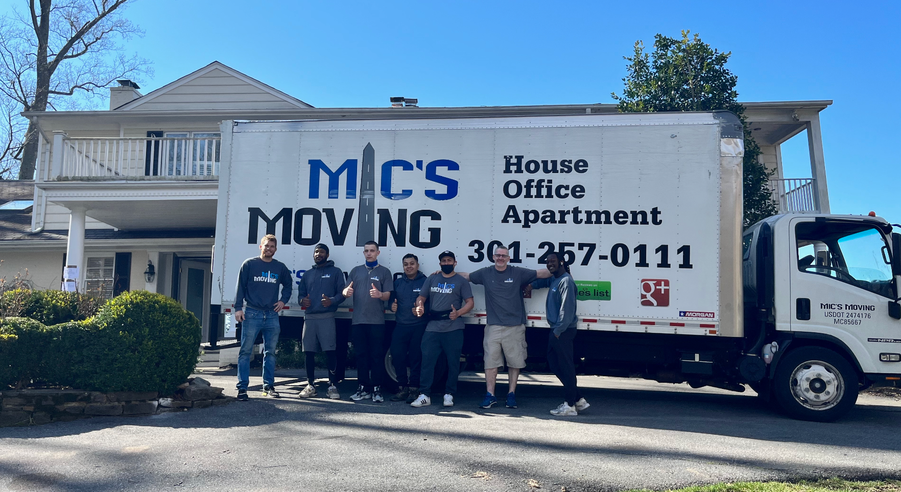 A group of men are standing in front of a moving truck.